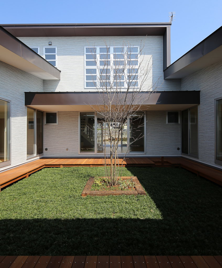 スタイルのある建物に囲まれたウッドデッキの中庭